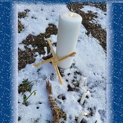 Jahreskreisfest Imbolc: Kerzen, Brigidkreuz und Schneeglöckchen auf verschneitem Boden