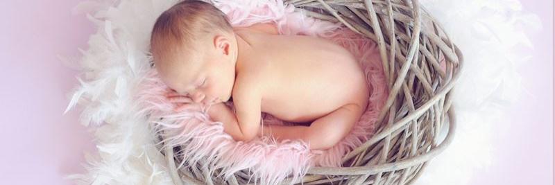 Baby im Weidenkorb rosa Hintergrund